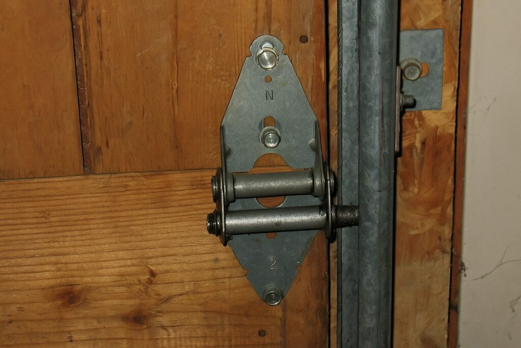 Close-up of a metal hinge and roller assembly during a garage door tune-up, ensuring proper alignment and smooth track movement.